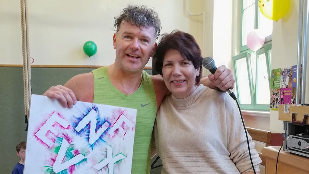 Schulleiterin Diana Jakob übergibt Tanzlehrer Michael Hirschel ein Bild mit tanzenden Buchstaben, welches die Kinder gemalt haben.