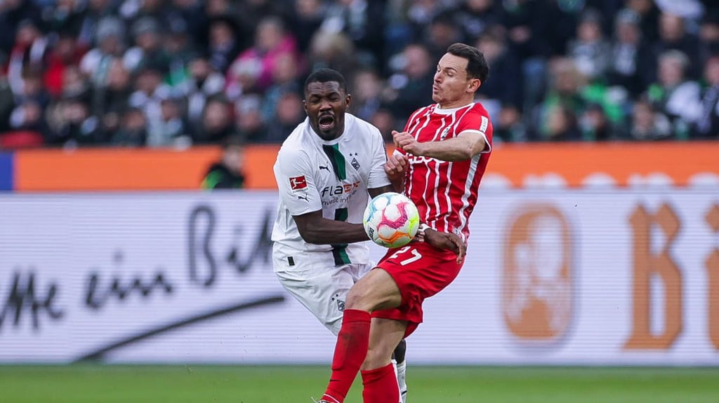 Marcus Thuram (Borussia Mönchengladbach) und Freiburgs Nicolas Höfler (r.) stoßen zusammen.