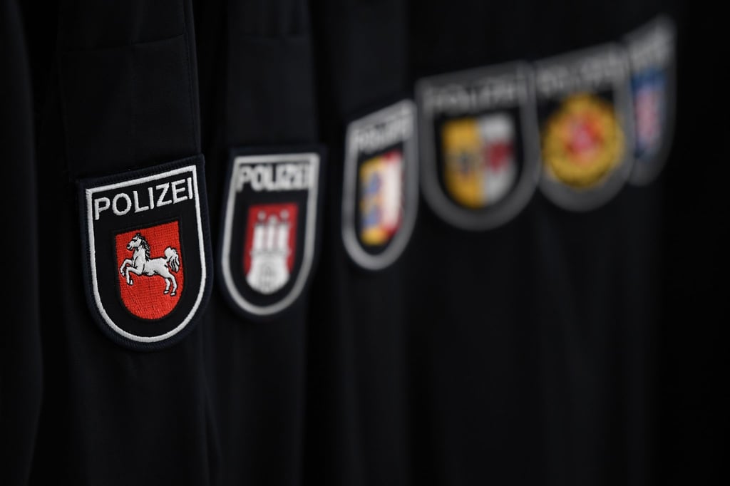 Verschiedene Wappen mit dem Schriftzug "Polizei" sind an Ärmeln von Einsatzkleidung zu sehen.