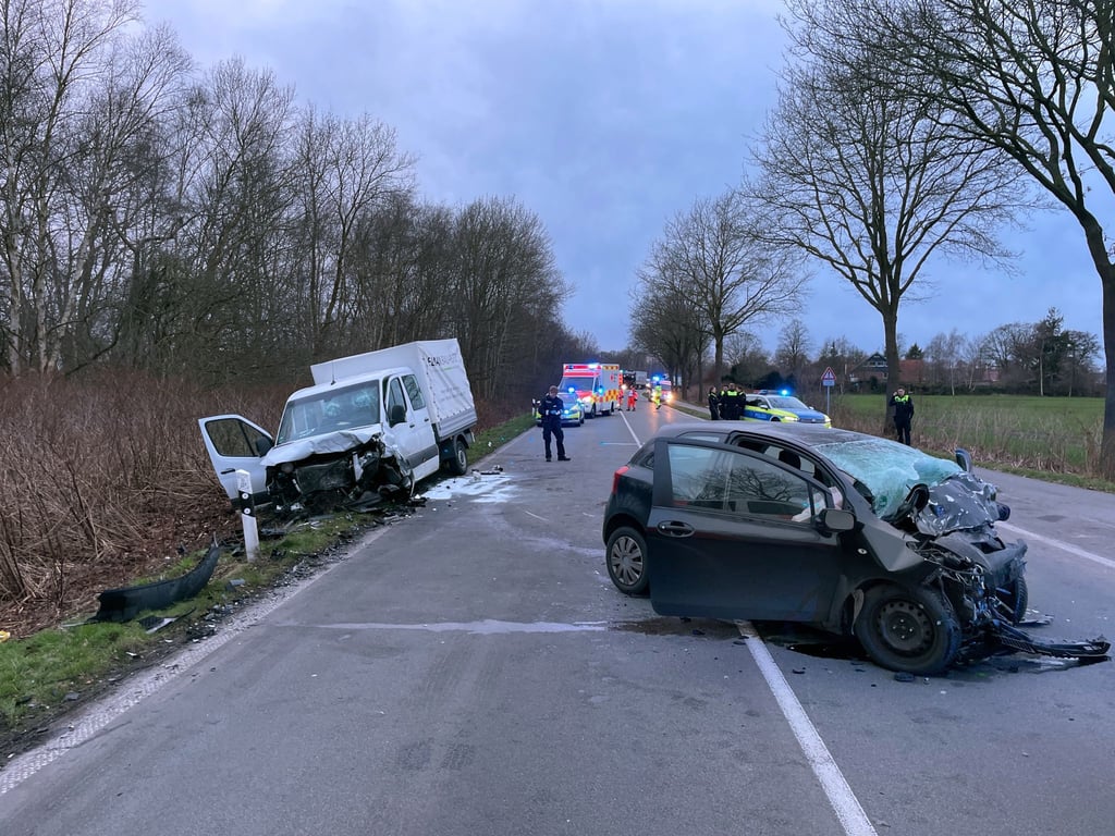 Polizisten und Helfer stehen an einer Unfallstelle auf einer Straße in Edewecht westlich von Oldenburg.