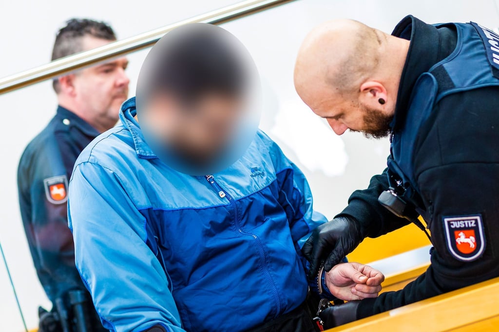 Ein Justizmitarbeiter löst bei einem der beiden Angeklagten die Handschellen.