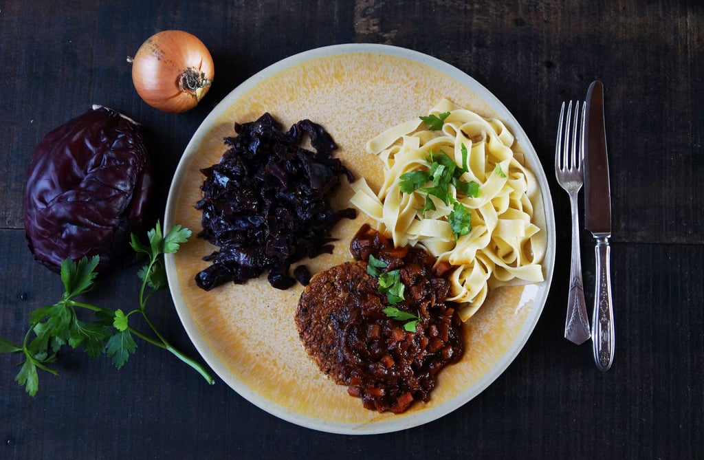 Ein luftiges Tagliatelle-Knäuel bildet mit weihnachtlichem Rotkraut und der krossen Veggie-Frikadelle ein Trio auf dem Teller.