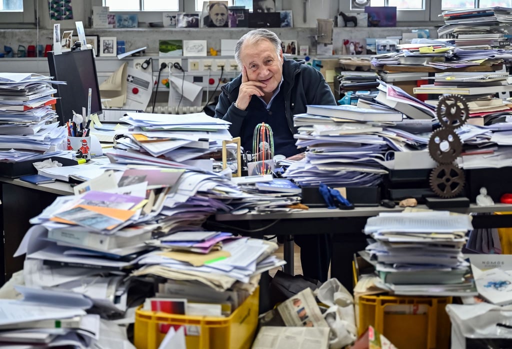 Peter Weibel, Künstler und Direktor des Zentrum für Kunst und Medien (ZKM), sitzt in seinem Büro zwischen aufgetürmtem Papierstapeln.