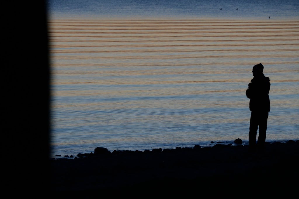 IEin Mann steht am Ufer des Bodensees.