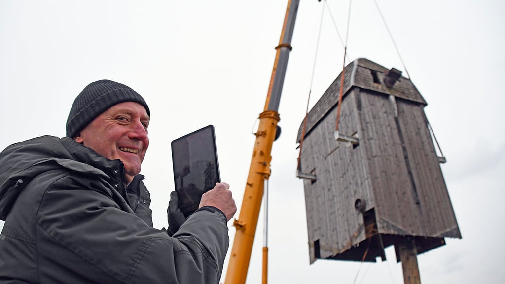 Mühlenbesitzer Helmut Russ aus Berlin nimmt das Aufsetzen der Windmühle auf den Bock mit der Videokamera seines Tablets auf.