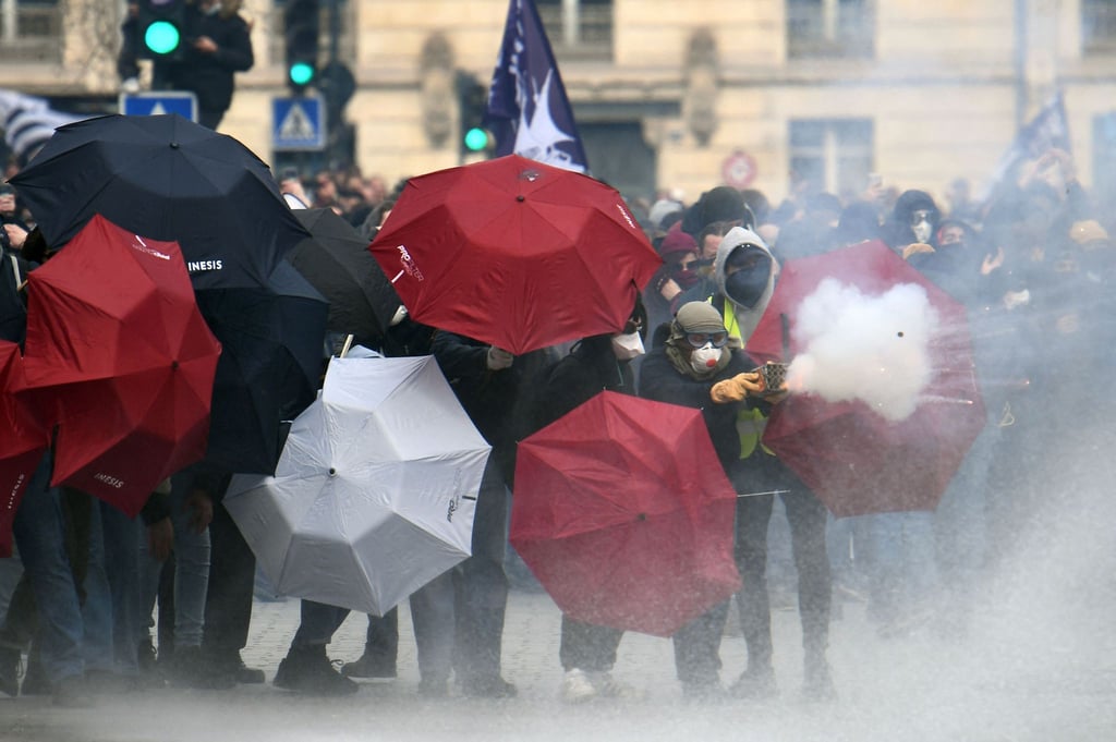 Feuerwerkskörper werden abgeschossen, Menschen verstecken sich hinter Regenschirmen: Proteste in Nantes.