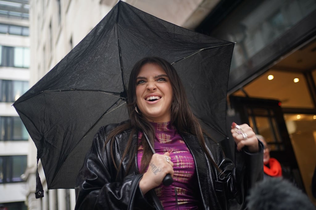 Sängerin Mae Muller steht mit einem Regenschirm vor dem BBC Wogan House. Gastgeberland Großbritannien schickt beim diesjährigen Eurovision Song Contest (ESC) die englische Sängerin Mae Muller ins Rennen.