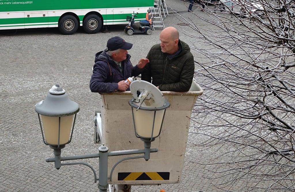 Elektromeister Paul Lehmann (l) setzt kurz vor seinem 80. Geburtstag mit dem Bürgermeister Karsten Eule-Prütz eine LED-Leuchte in eine Straßenlampe ein.