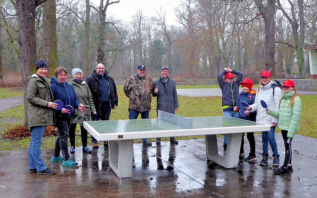 Erwachsene und Kinder stehen an der neuen Tischtennisplatte.