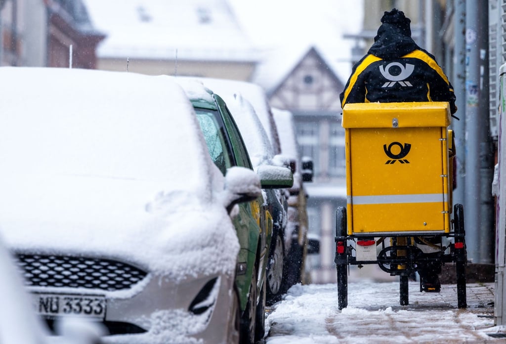 Eine Briefträgerin ist mit ihrem Fahrrad in der Altstadt von Schwerin unterwegs.