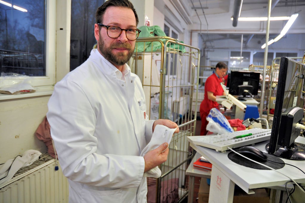 Standortleiter Marcus Schröder zeigt den Barcode, mit dem jedes Wäscheteil bestückt ist.