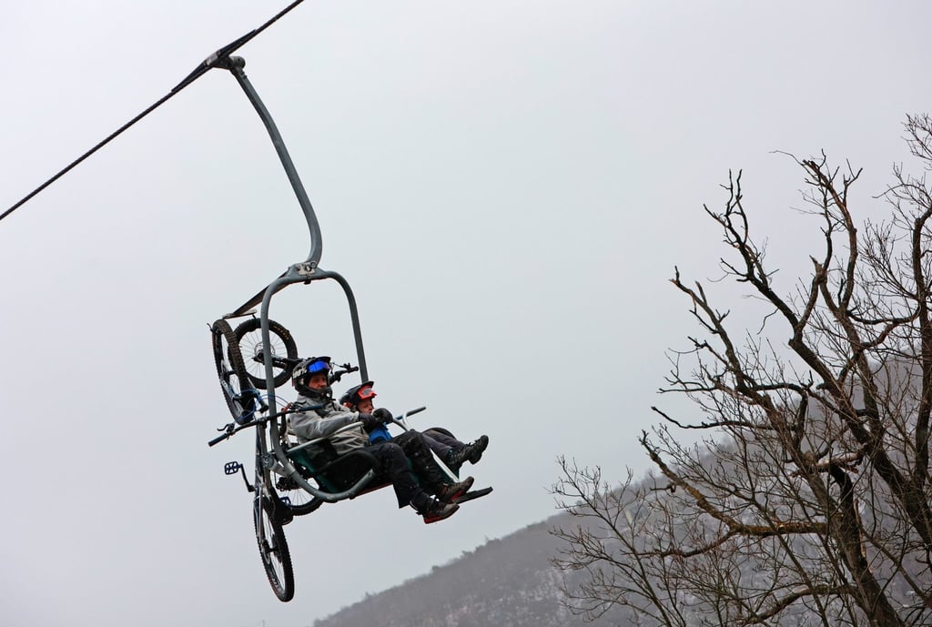 Zwei Männer sitzen mit ihren Mountainbikes in einem Sessellift.