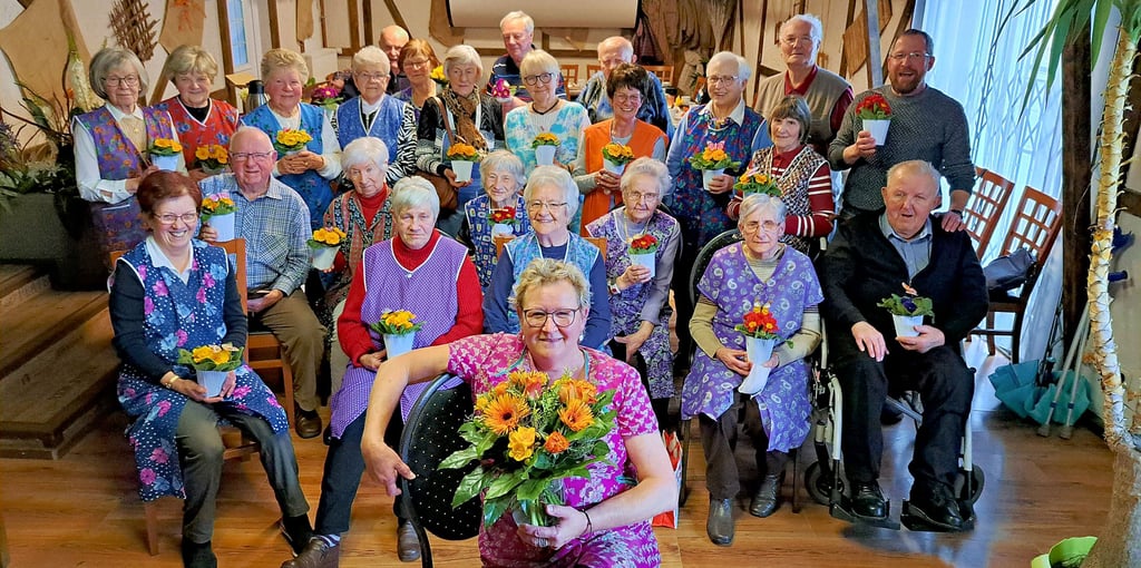 Liana Quiel (vorn) hat den Blumenstrauß der Woche, von der Blumenboutique Meinhardt zur Verfügung gestellt, von den Gästen des Molmecker Kaffeeklatschs bekommen. Zum Treffen am Frauentag war das Motto „Kittelschürze“, wofür die Damen Blümchen bekamen.