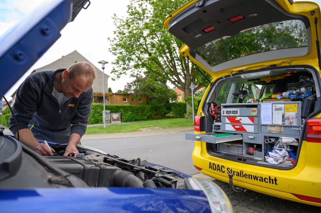 Ein Pannenhelfer beim ADAC beschriftet eine neue Autobatterie, die er ausgewechselt hat.