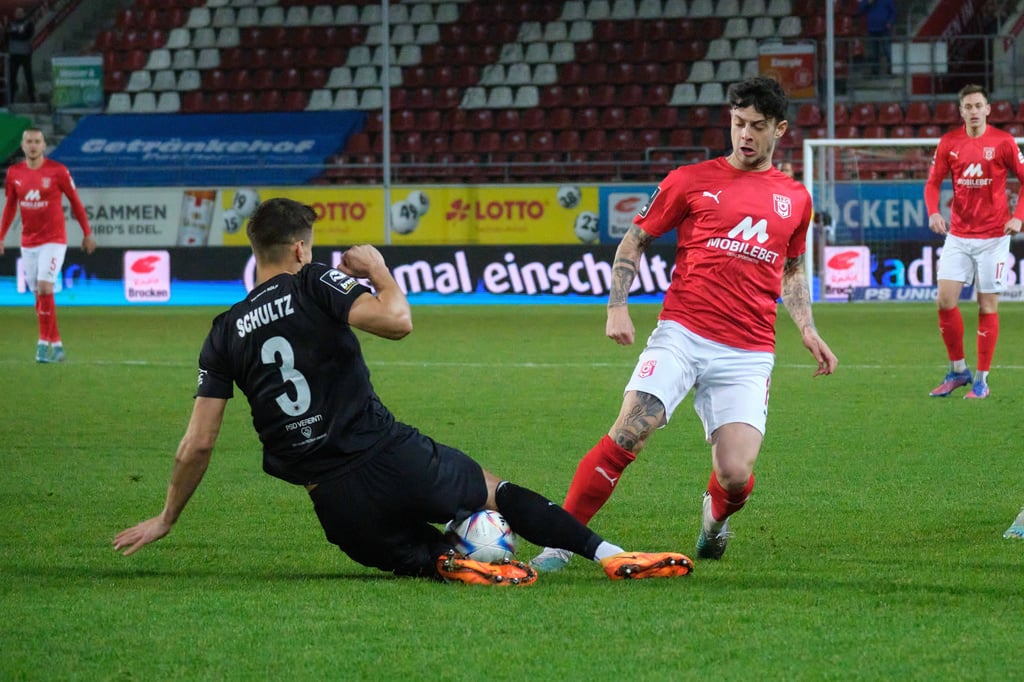 Kölns Michael Schultz grätscht gegen Halles Aaron Herzog.