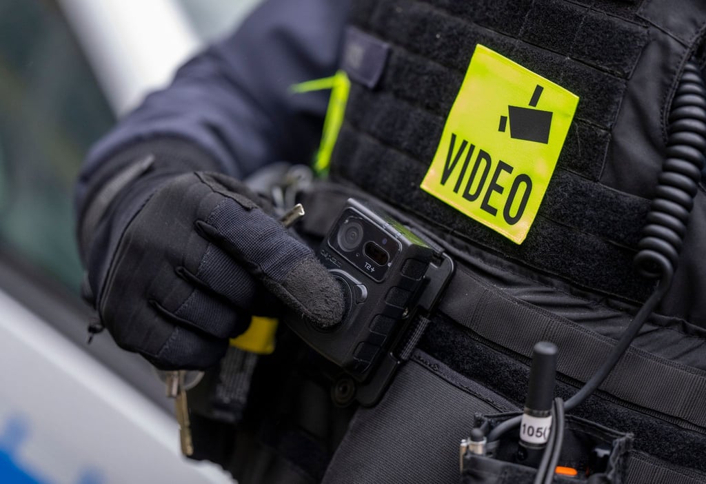 Ein Polizist schaltet die Bodycam auf seiner Uniform ein.