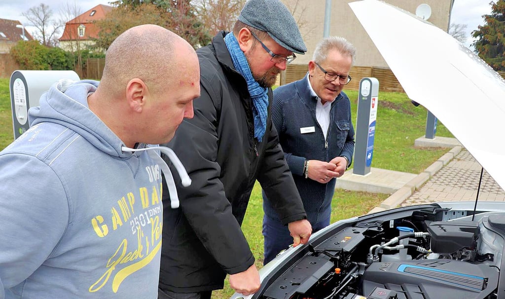 Fuhrpark-Leiter Nico Melzer und Landrat Martin Stichnoth lassen sich Bernd Görsch, Verkaufsberater von Schubert Motors, den Elektroantrieb erklären (von links).