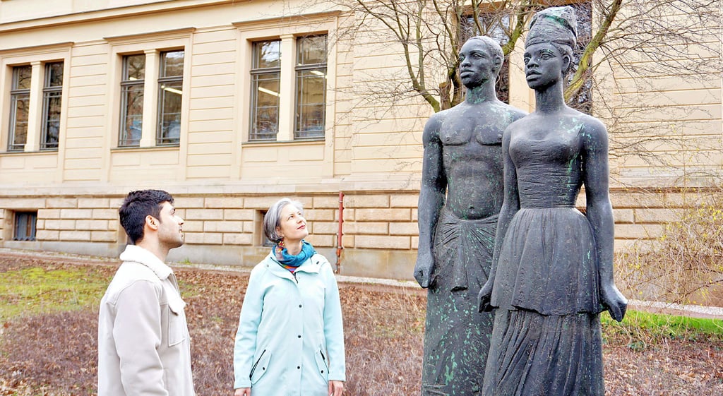 Alaa Alrefaie und Karola Richter stehen vor der Bronzeplastik „Freies Afrika“, die oft fälschlich mit Anton Wilhelm Amo in Verbindung gebracht wird. Sollte die Skulptur ursprünglich die sozialistische Idee verkörpern, transportiert sie aus heutiger Sicht rassistische Klischees.