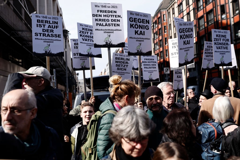 Menschen im Publikum halten Schilder am 175. Jahrestag der Märzrevolution hoch.