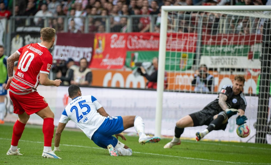 Schalkes Torwart Ralf Fährmann (r) und Moritz Jenz können das Tor von Augsburgs Arne Maier (l) nicht verhindern.
