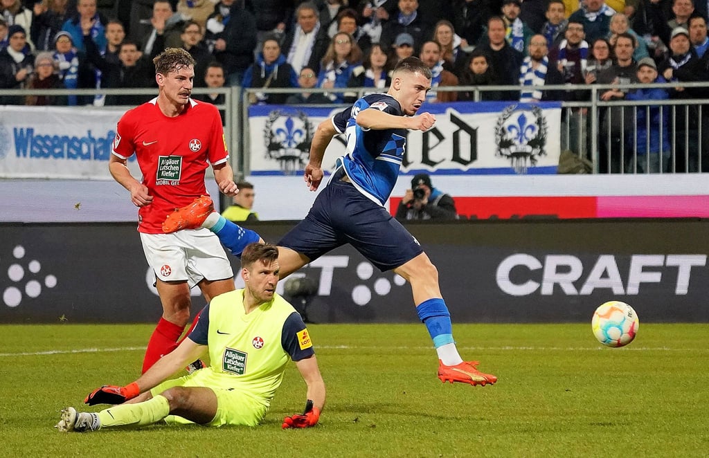 Darmstadts Filip Stojilkovic (r) erzielt den Treffer zum 2:0. Kaiserslauterns Kevin Kraus (l) und Torwart Andreas Luthe (M) schauen hinterher.