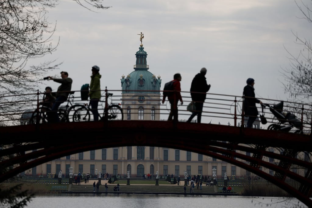 Passanten gehen und fahren mit dem Fahrrad auf einer Brücke in der Parkanlage vor dem Schloss Charlottenburg.
