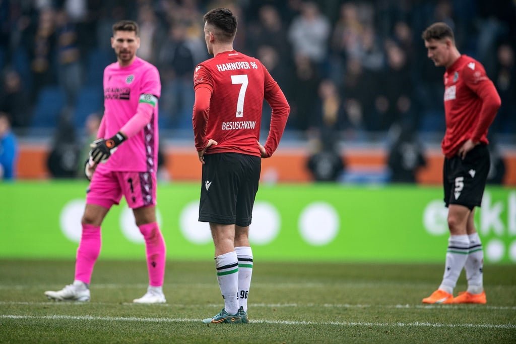 Hannovers Torwart Ron-Robert Zieler (l-r), Hannovers Max Besuschkow und Hannovers Phil Neumann stehen nach dem Schlusspfiff enttäuscht auf dem Platz.