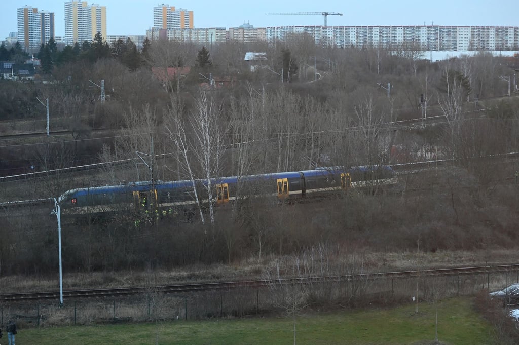 Einsatzkräfte stehen an der Regionalbahnstrecke unweit der Gensinger Straße in Friedrichsfelde. Ein Regionalzug ist nahe dem S-Bahnhof Friedrichsfelde-Ost mit einer herabhängenden Oberleitung zusammengestoßen.