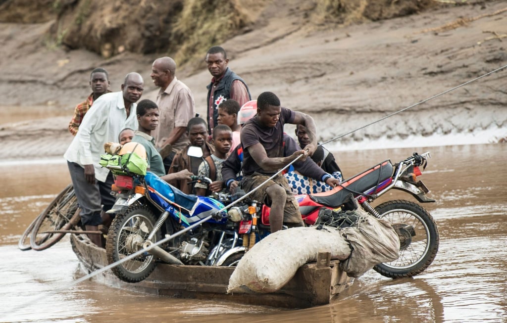 Männer transportieren in Malawi ihre geretteten Habseligkeiten mit einem Holzboot.
