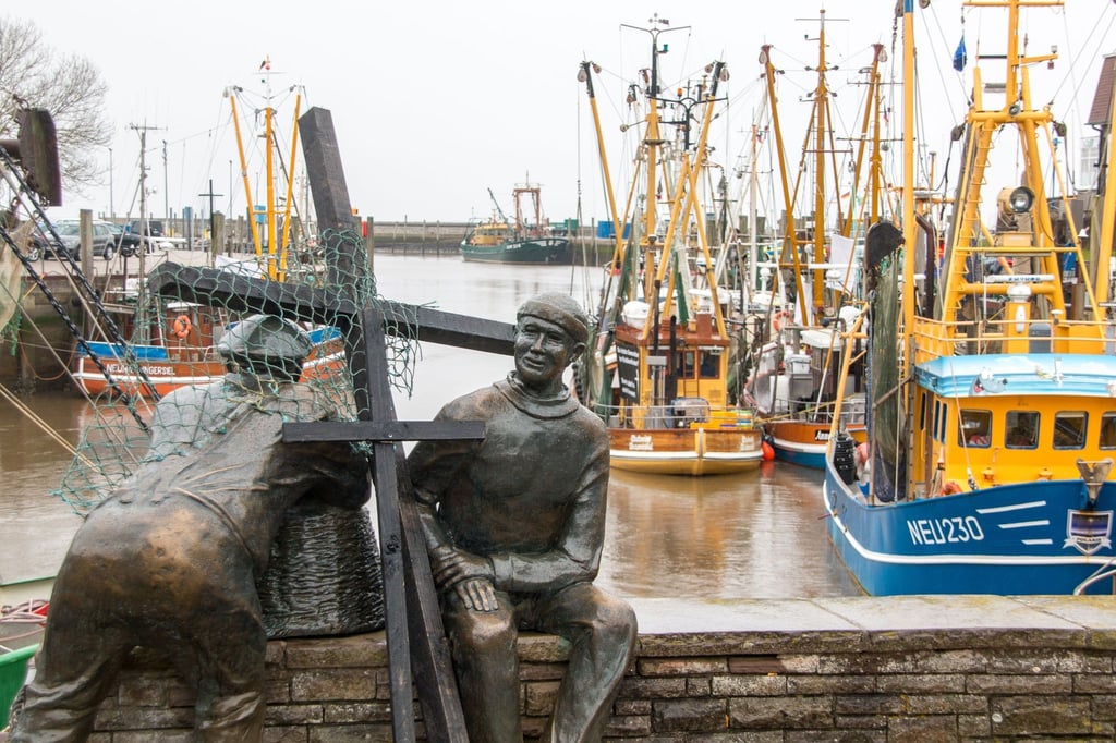 Schwarze Holzkreuze lehnen an der Bronezeskulptur „Alt- und Jungfischer“ im Hafen in Neuharlingersiel. Das Fischen mit Grundschleppnetzen steht in der Kritik.