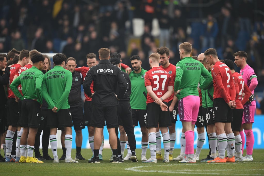 Hannover Spieler stehen nach dem Schlusspfiff im Kreis auf dem Platz.