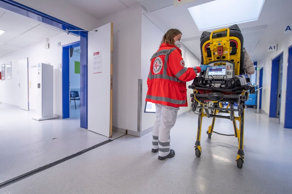 Ein Notfallsanitäterin schiebt eine Seniorin auf einer Trage in die Notaufnahme eines Krankenhauses