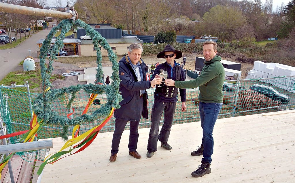 WBG-Geschäftsführer Christian Puschmann, Zimmerer Daniel Truxa und und Architekt André Grundmann (v. l.) stoßen am Richtkranz an.
