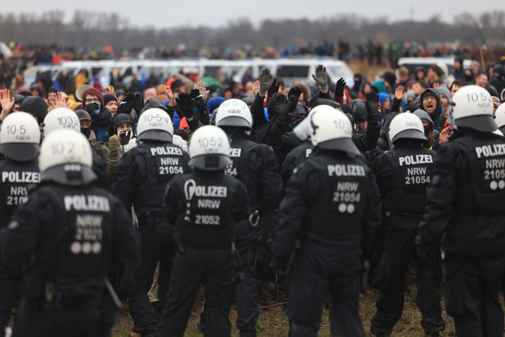 Polizisten und Demonstranten stehen sich bei der Demonstration von Klimaaktivisten am Rande des Braunkohletagebaus bei Lützerath gegenüber.