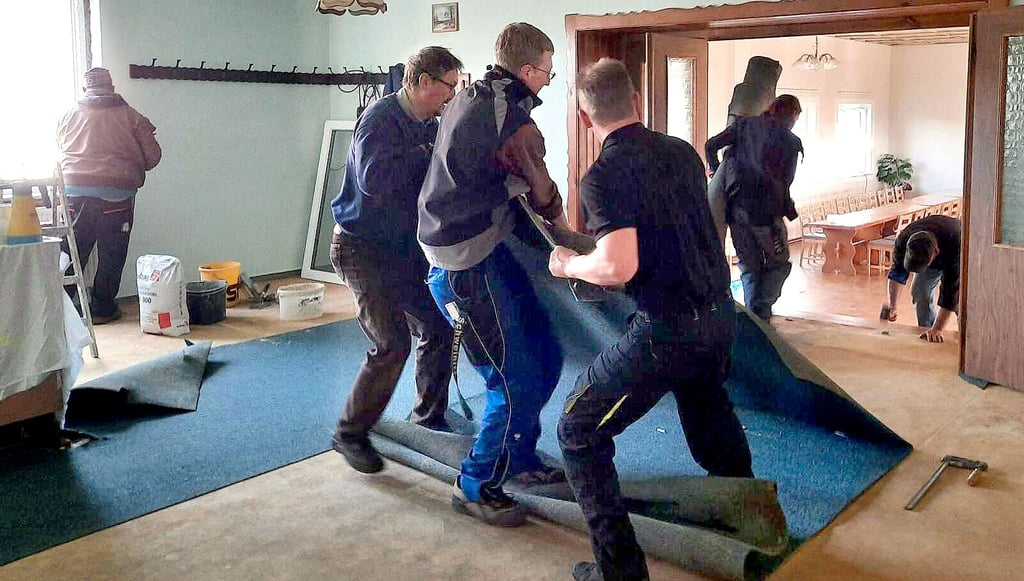 Mit vereinten Kräften wird in der Gaststube Dixförda der alte Fußbodenbelag herausgerissen.