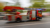 Ein Feuerwehrfahrzeug mit Drehleiter fährt zu einem Einsatz.