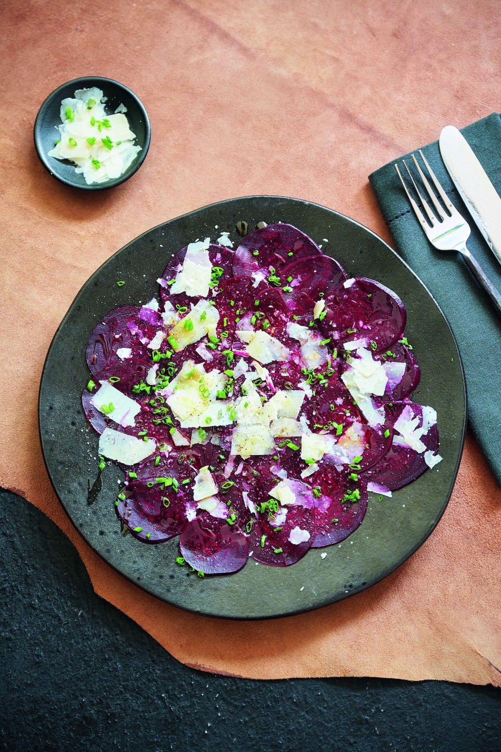 Die hauchdünnen Rote-Bete-Scheiben werden mit einem Dressing aus Öl und Himbeeressig beträufelt und mit Parmesan und Schnittlauch dekoriert.