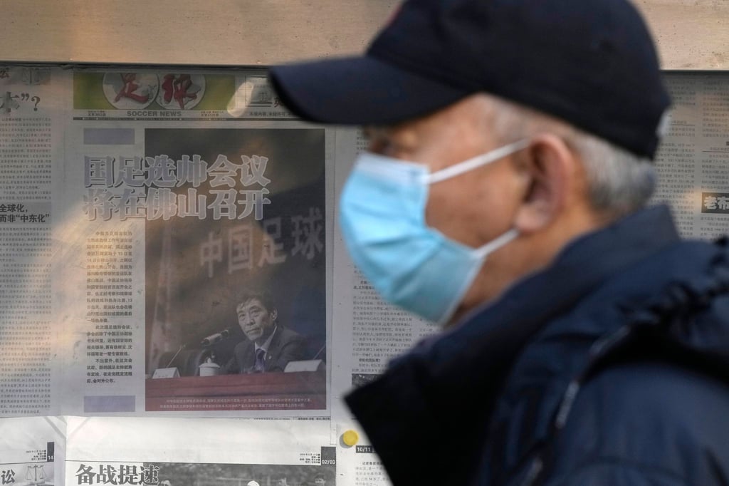 Ein Mann geht in Peking an einem Kiosk vorbei, der eine Zeitung mit einem Foto von Chen Xuyuan, dem Chef des chinesischen Fußballverbands, ausgehängt hat.