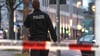 Ein Polizist geht hinter einem Absperrband entlang.