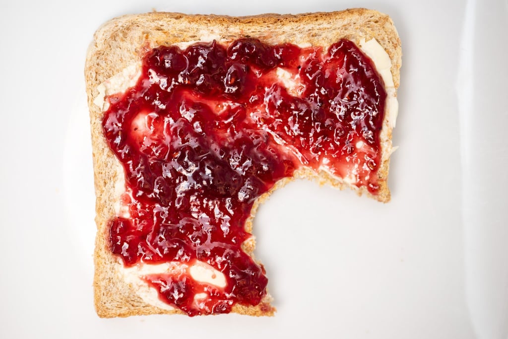 Ein Toastbrot mit Himbeermarmelade liegt auf auf einem Teller.