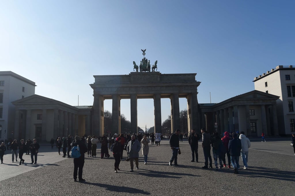 Touristen stehen vor dem Brandenburger Tor in Berlin.