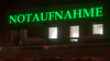 Der Schriftzug „Notaufnahme“ hängt in leuchtendem Grün an einem Krankenhaus.