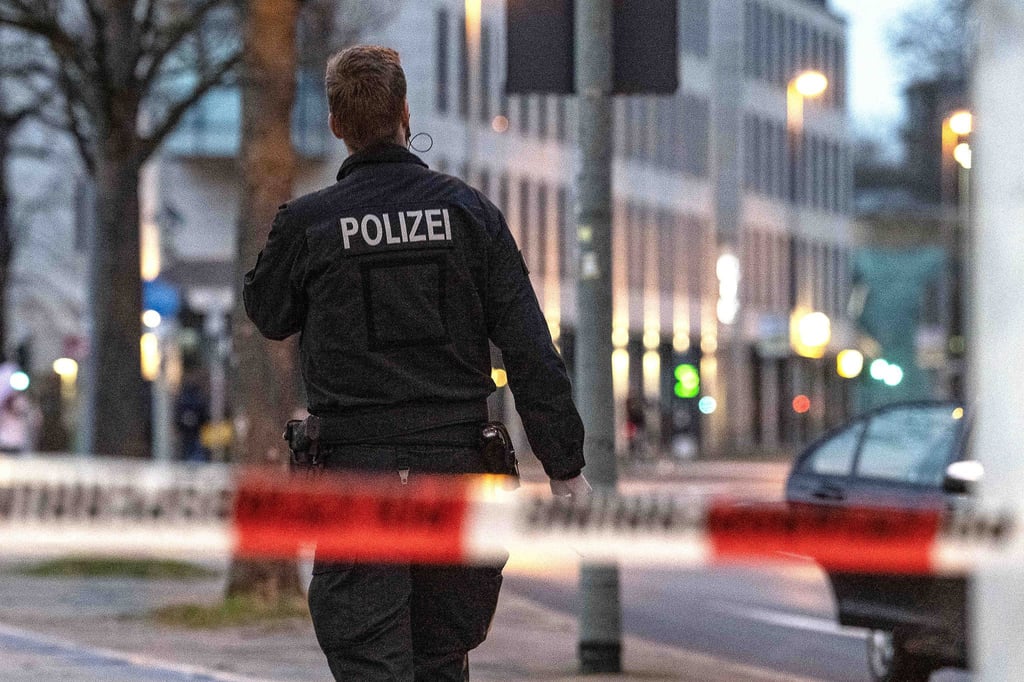 Ein Polizist geht hinter einem Absperrband entlang.