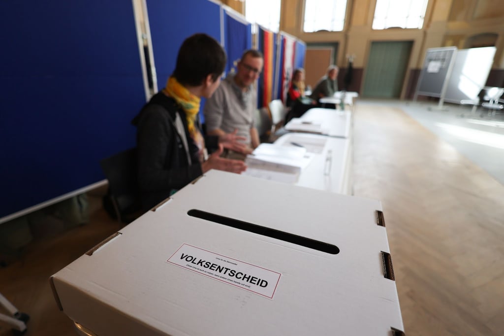 Wahlhelfer sitzen vor einer Wahlurne in einem Wahllokal im Bildungs- und Kulturzentrum Peter Edel in Berlin-Weissensee.