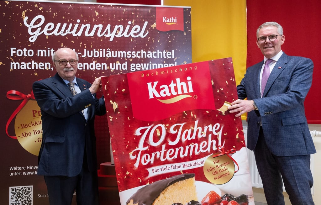 Rainer Thiele (l), ehemaliger Geschäftsführer der Kathi Rainer Thiele GmbH, und sein Sohn, Marco Thiele, Kathi Geschäftsführer, stehen an einer übergroßen Packung der Jubiläumsbackmischung für Kathi Tortenmehl.