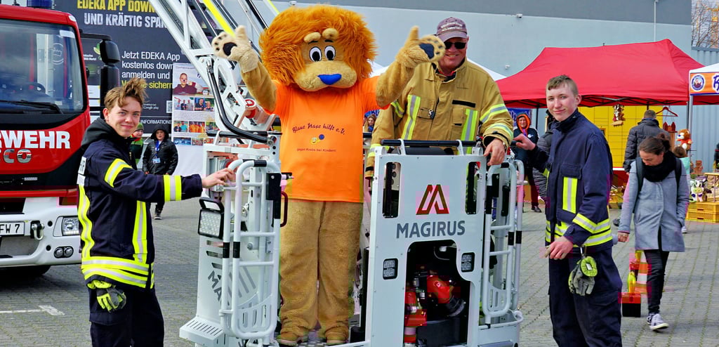 Der orangefarbene Löwe mit der blauen Nase ist das Maskottchen des Vereins „Blaue Nase hilft“. Wo er auftaucht, werden Spenden für Familien mit krebskranken Kindern gesammelt. Damit viele Menschen stehen bleiben und davon erfahren, war auch Wolmirstedts, später auch die Zielitzer Feuerwehr am E-Center.