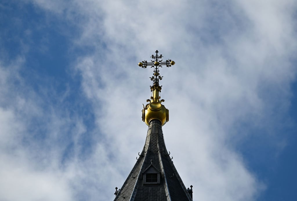 Ein Kreuz bildet den Abschluss des Kirchturms.