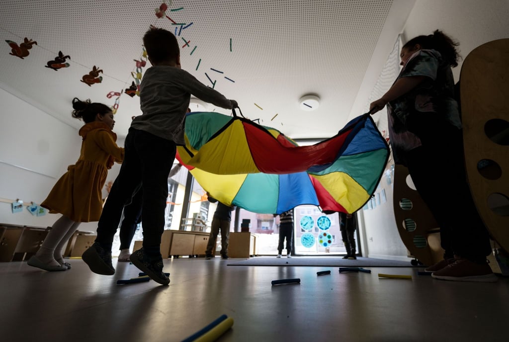 Kinder einer Kindergartengruppe der Kita Hoppsala spielen in einem Gruppenraum mit ihrern Erzieherinnen.