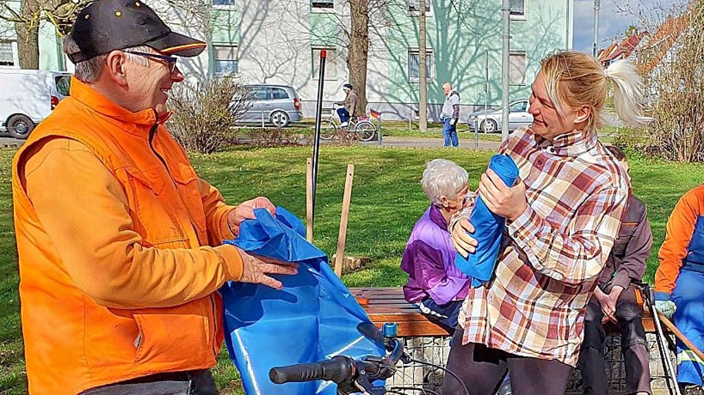 Sindy Krause gibt am Markt Müllsäcke an die Teilnehmer aus.