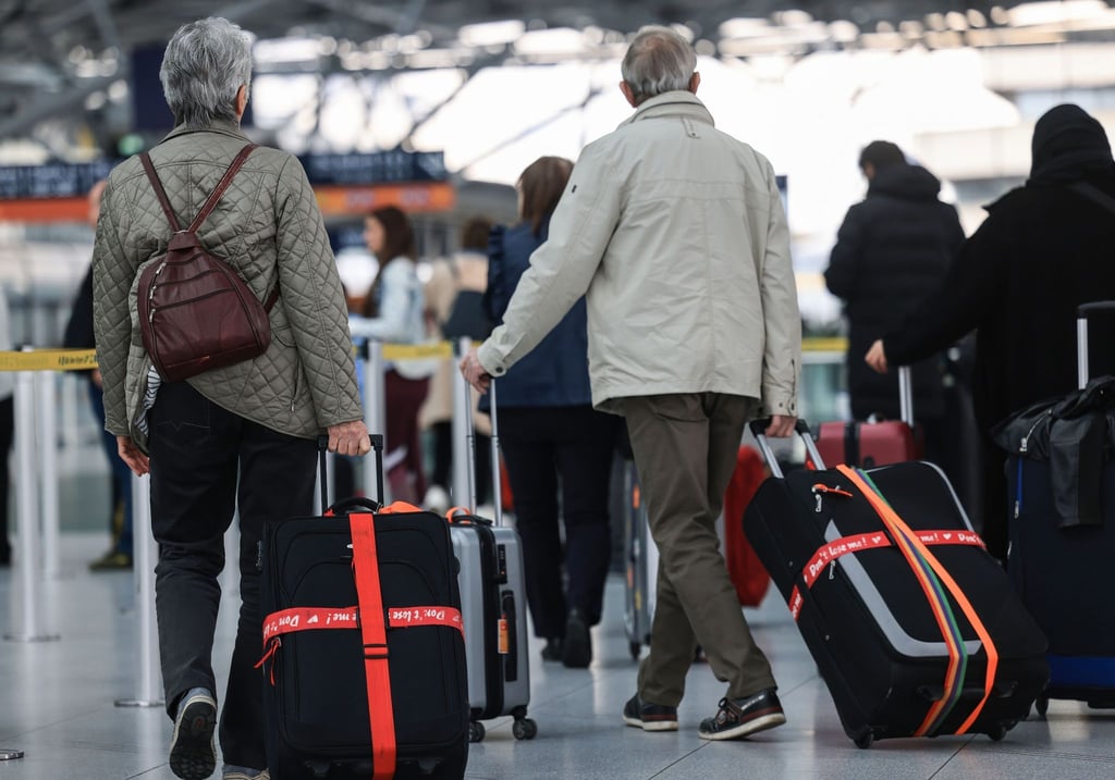 Ältere Reisende gehen am Flughafen mit Reisekoffern durch das Terminal.